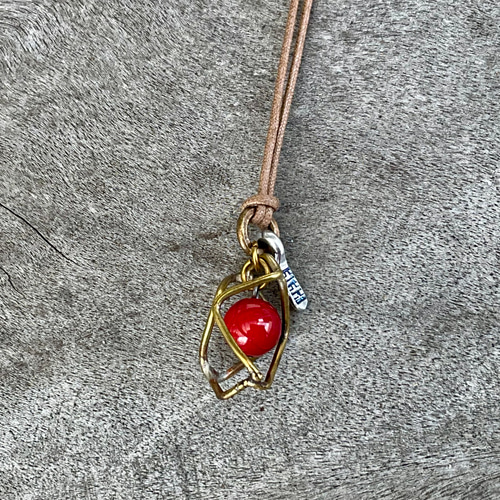 魔を除ける意味の赤珊瑚を、真鍮のサークルで包んだ小ぶりの一粒