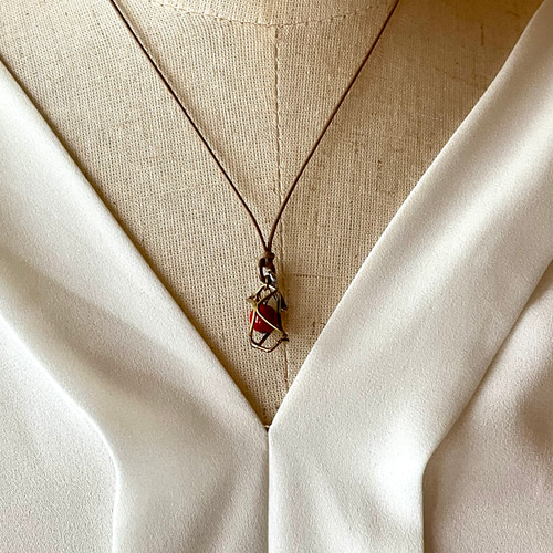 魔を除ける意味の赤珊瑚を、真鍮のサークルで包んだ小ぶりの一粒