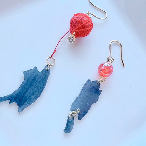 ぷらぷら揺れる毛糸玉で遊ぶ黒猫と首ねっこをつままれる黒猫の ぷらぷら揺れる毛糸玉で遊ぶ黒猫と首ねっこをつままれる黒猫の