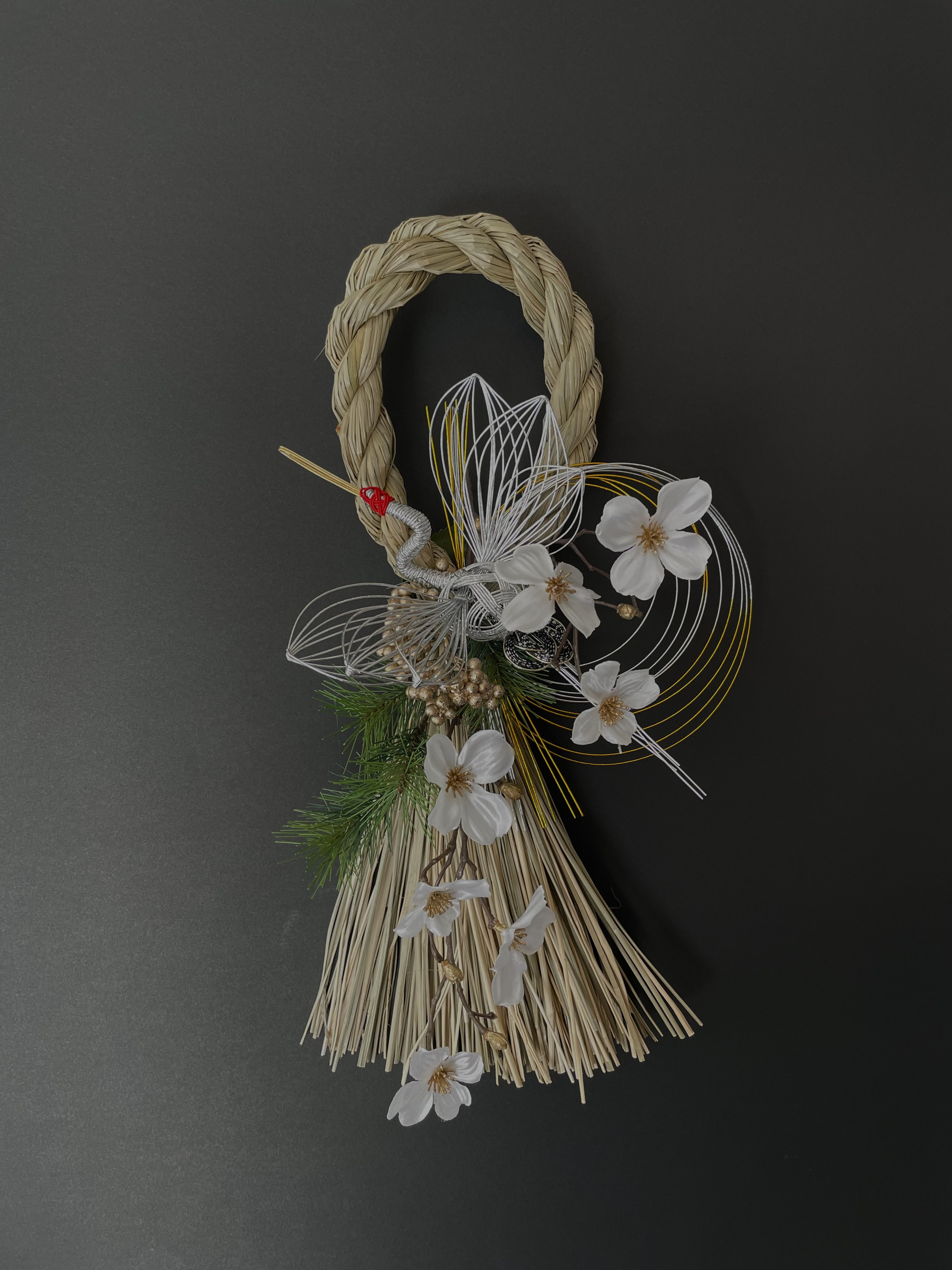 お花畑の上を鶴が舞っているプルモサムとケイトウのお正月しめ縄