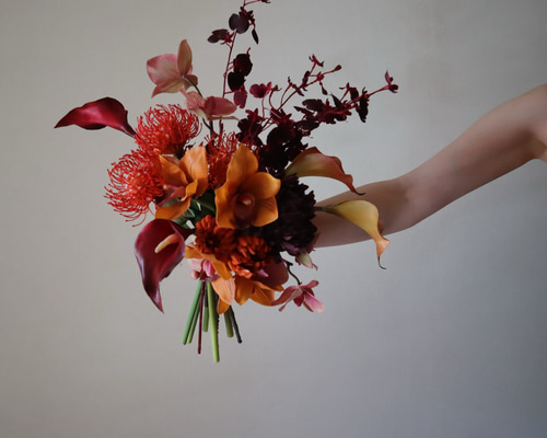 ワインカラーとテラコッタカラーの動きのあるクラッチブーケ