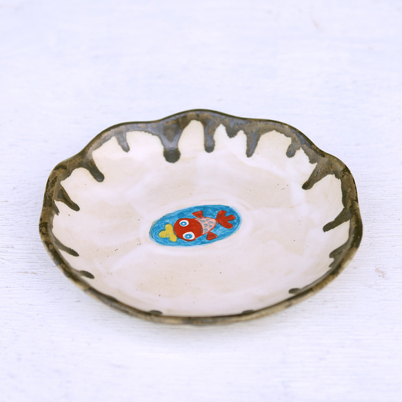 一個白色的盤子，上面畫著一條戴著黃色帽子的金魚在游泳。 第2張的照片