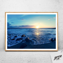 絶景夕暮れビーチ：太陽の落ちる海岸線、波立つ青い海と岩々 穏やかな空のグラデーション リラックス感溢れる自然景色ポスター 1枚目の画像