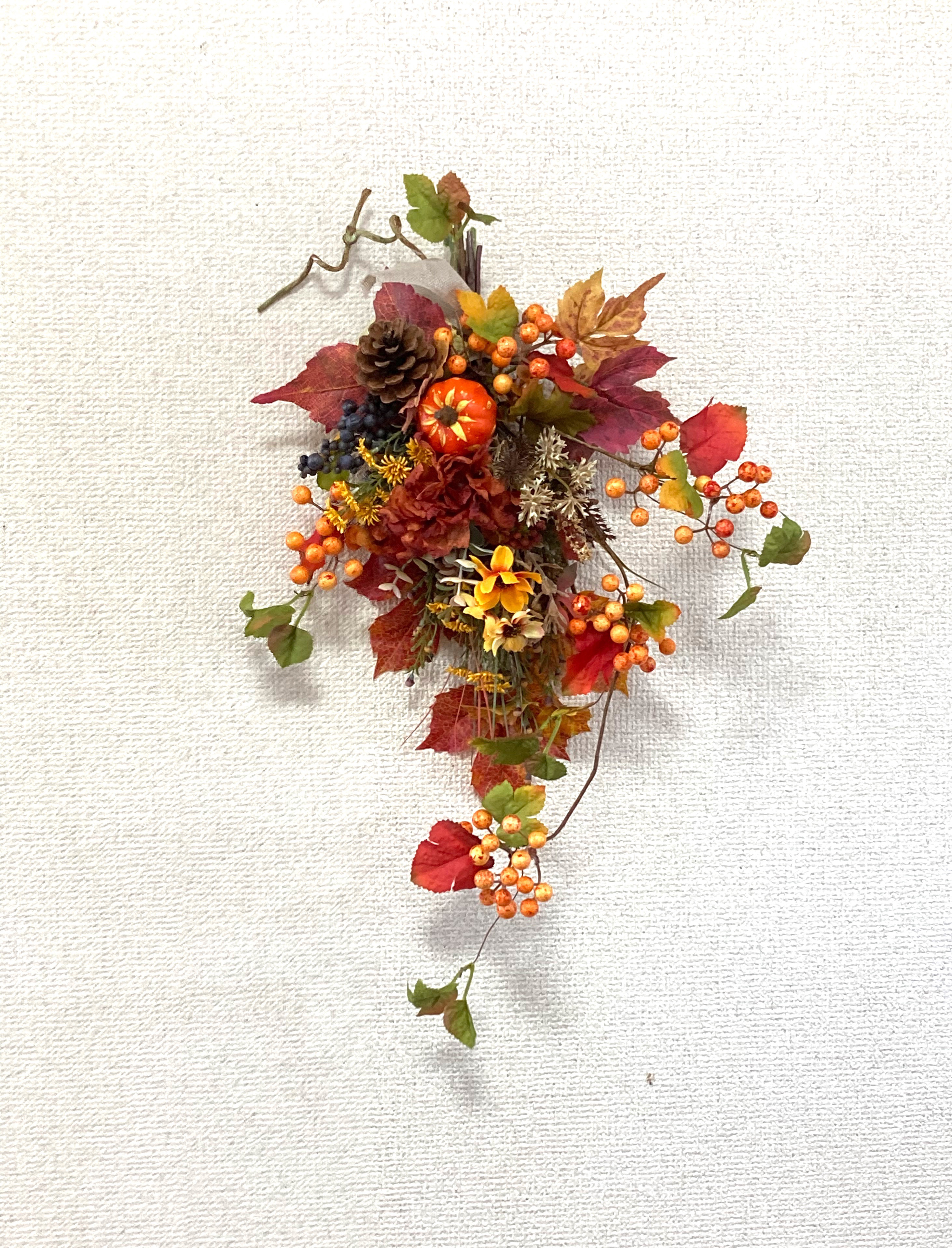 秋色に染まるごろ　やわらかい陽の色に染まった花たちと葉と木の実のスワッグ