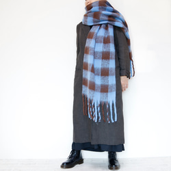 超大格子圍巾採用蓬鬆材質製成，藍色和棕色，非常適合作為禮物或單一色調服裝的點綴。 第2張的照片