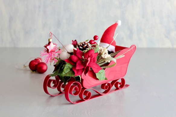 ソリに乗ったサンタクロースのポインセチアクリスマスアレンジ 1枚目の画像