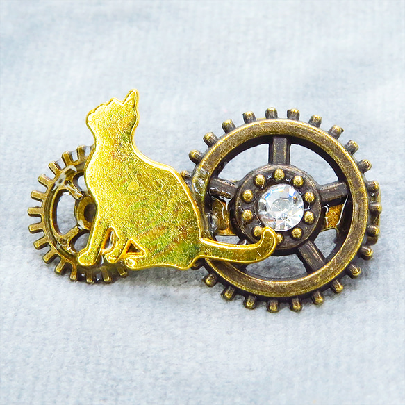 見上げる猫シルエットモチーフと歯車を組合せたコンパクトなスチームパンク風ブローチ バッジ アンティークゴールド 1枚目の画像