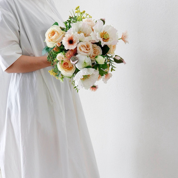 花屋が束ねる柔らかなオレンジ色のウェディングブーケ(ブートニア  