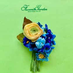イエローのラナキュラスとブルーフラワーの花束コサージュ 1枚目の画像
