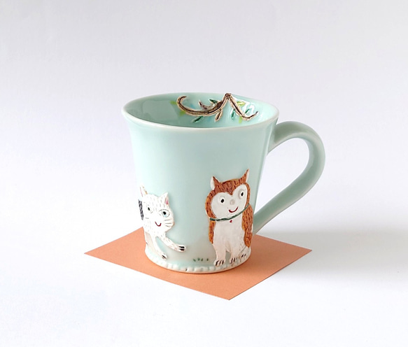 イヌさんとネコさん、道でバッタリ会う。　ゆっくりティータイム（イヌとネコと小鳥）マグカップ　磁器 1枚目の画像