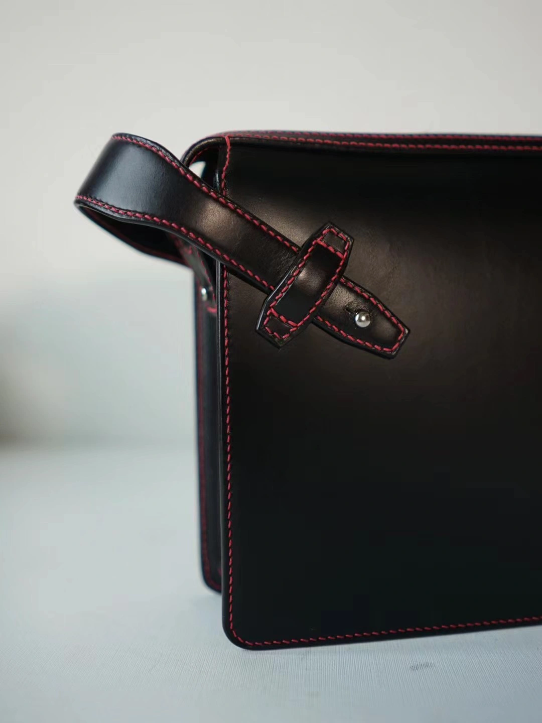 ミニマルと個性の融合。赤ステッチが映えるレザークラッチ