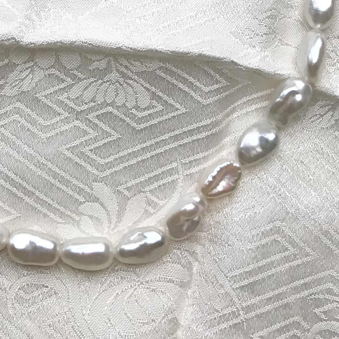 # 512 湖水芥子パール　1連　白に虹の干渉色　7×10ミリ　湖水真珠　ケシ　バロックパール