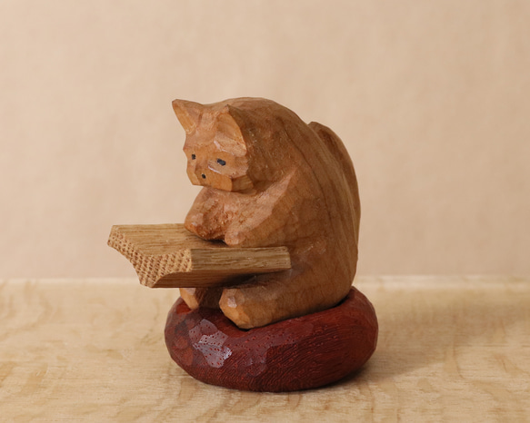 お気に入りの赤いクッションに座って本を読む猫」木彫り 猫 木製 ネコ