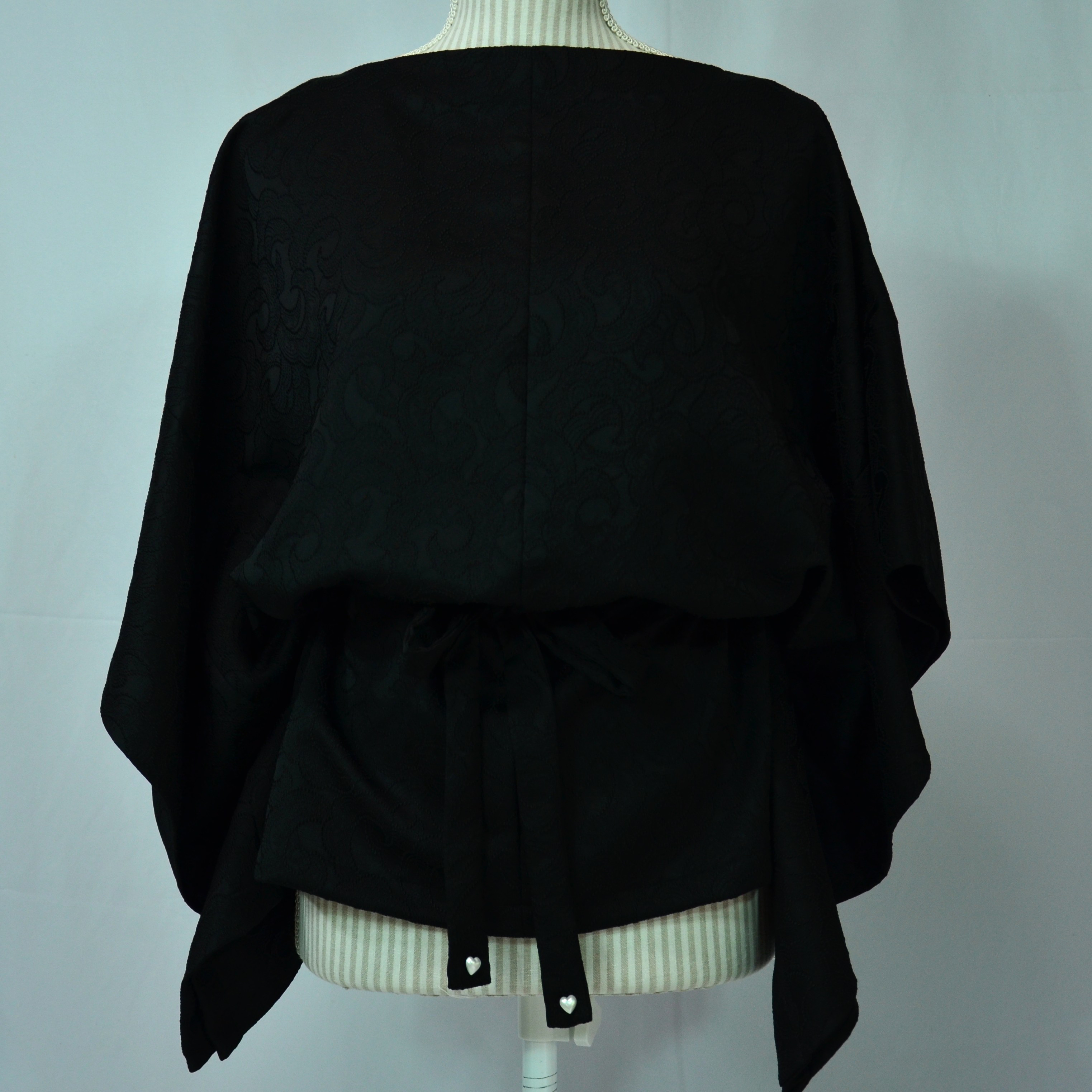 刺繍と見紛う紋意匠で精緻な花唐草を織り出した漆黒のブラウス