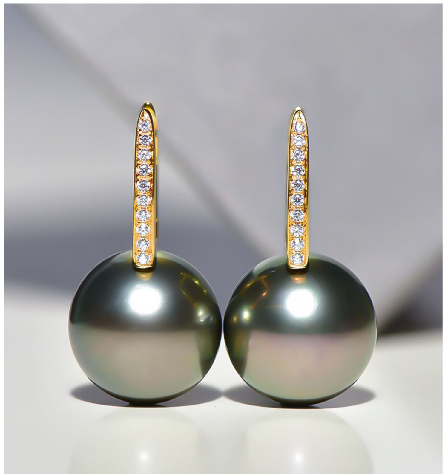18Kゴールド製、12～13mmタヒチ産ブラックパールのルミナイヤリング。ピーコックグリーンの輝きを放つバケットデザイン。クラシ