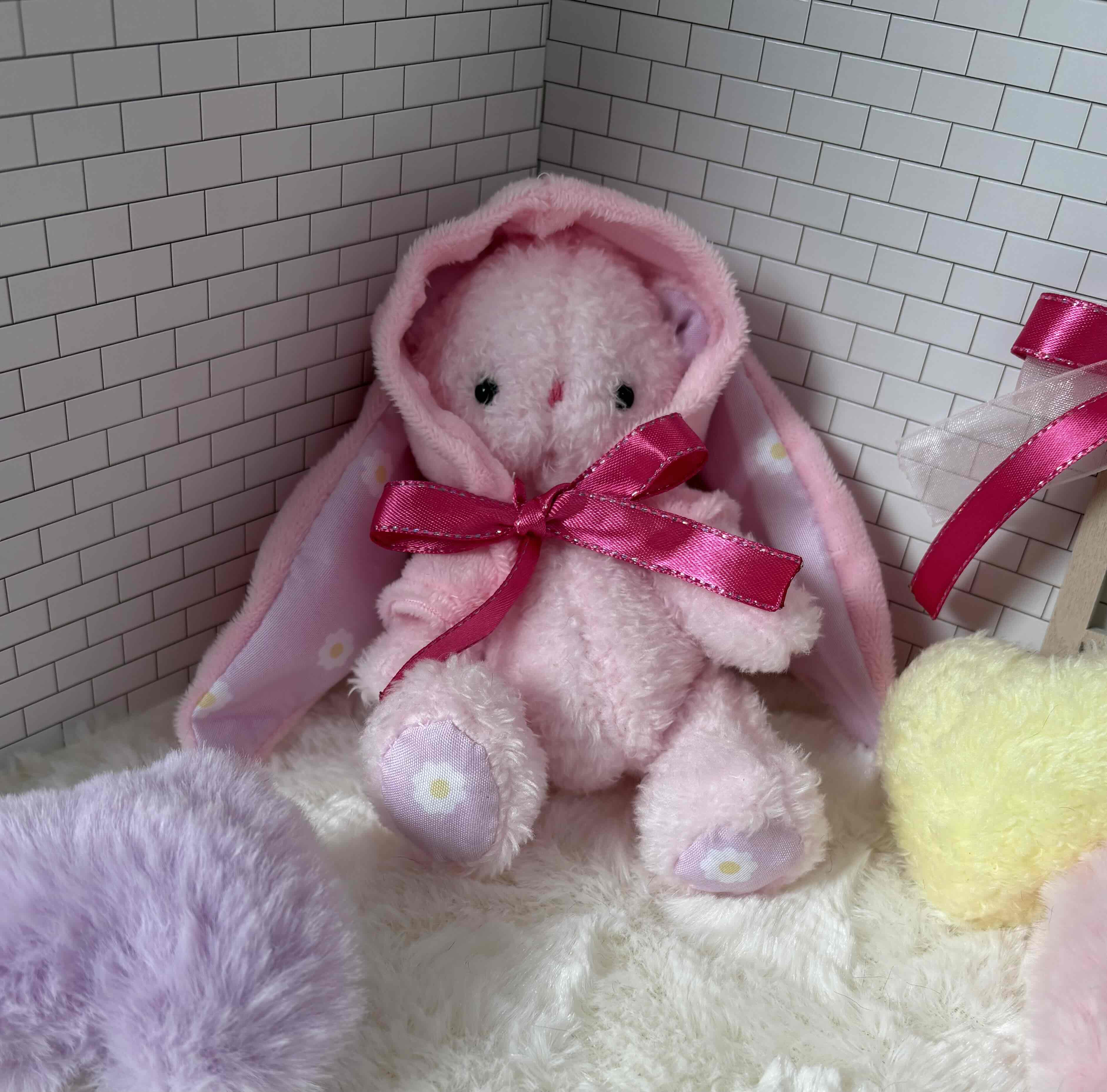 たれ耳付きフードをかぶったピンクのくまさんのぬいぐるみ