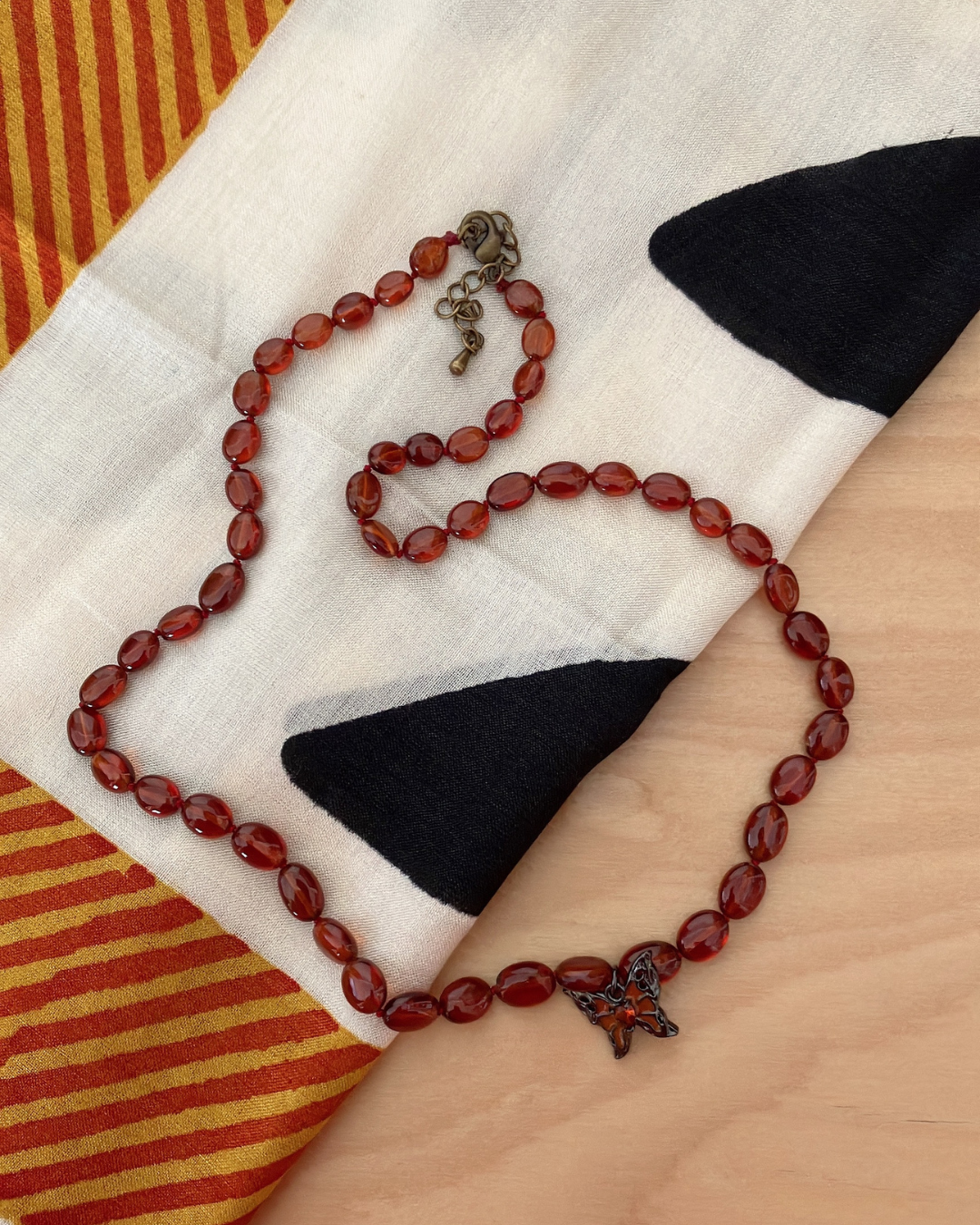 深紅に宿る光 — ヘソナイトガーネット × バタフライチャーム ネックレス（オールノット仕上げ）