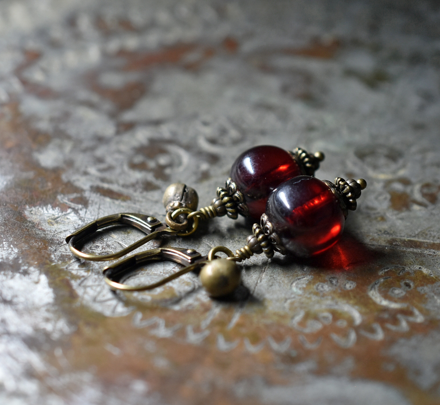 まん丸な柘榴色アフリカンアンバーと民族鈴のピアス