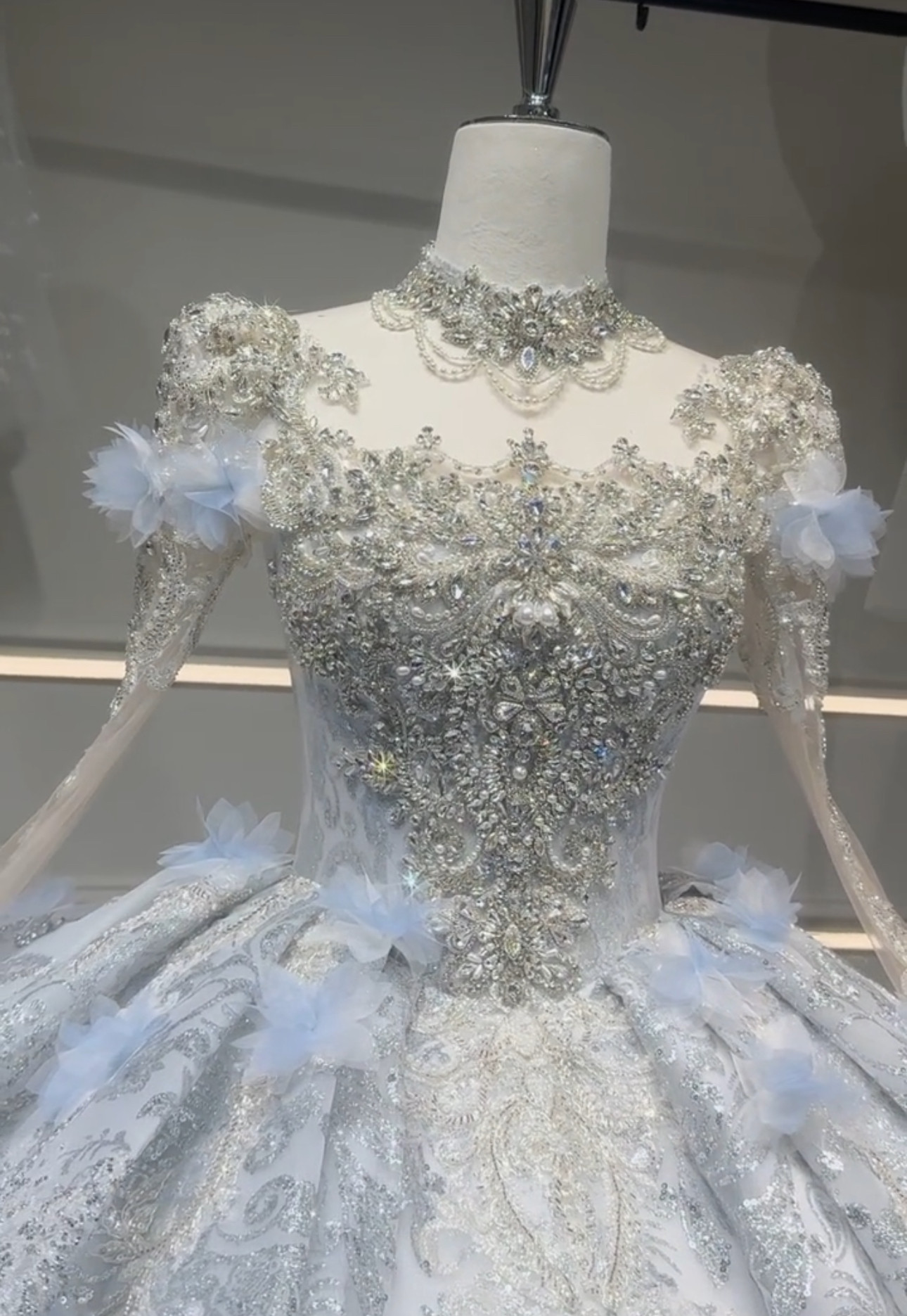 華やかなウェディングドレス　シースルー長袖　ブルーお花飾り　エレガント　ラメ入り　ラッフルスカート　背中見せ　ブライダル