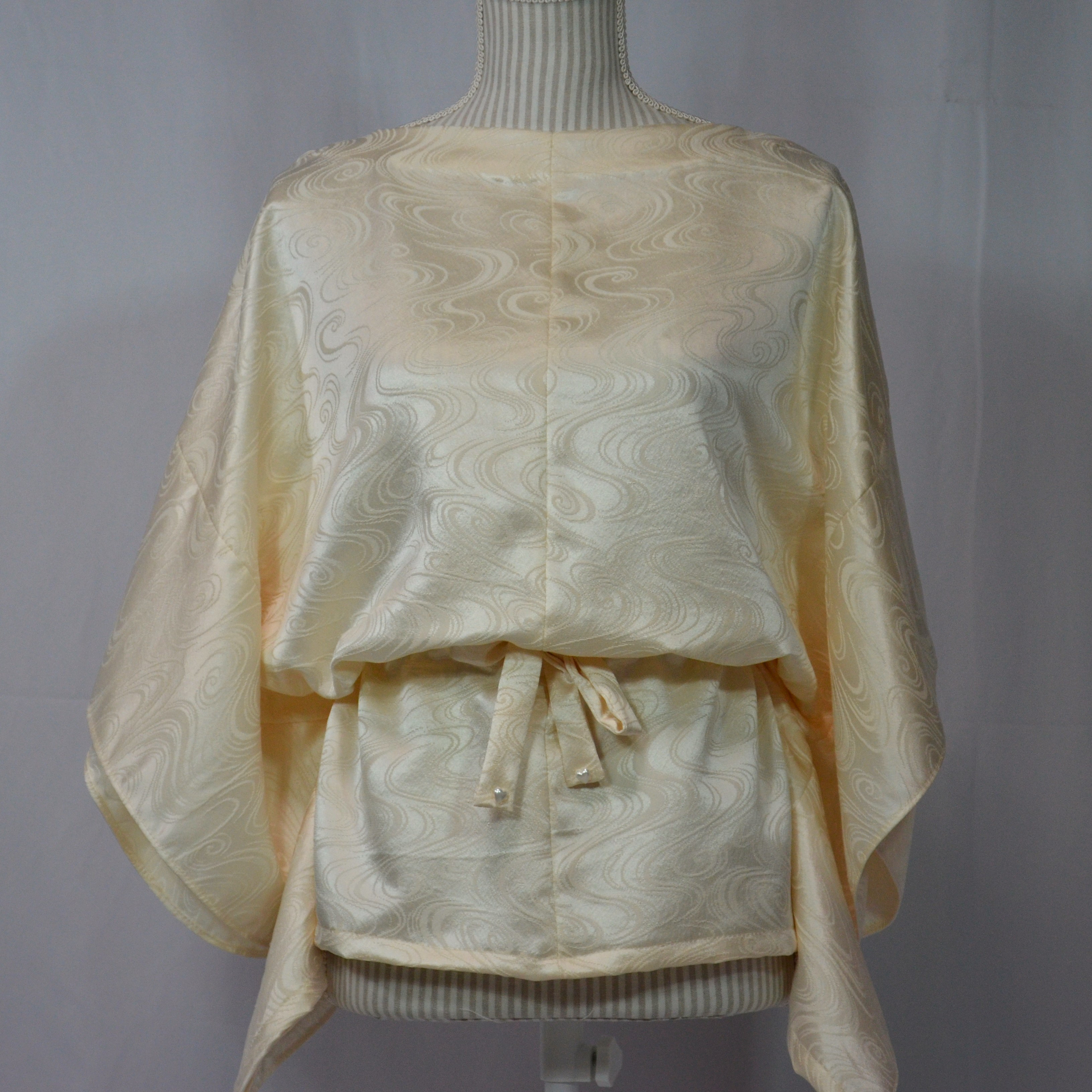 永遠の水を湛え、ミルクホワイトの綸子に煌めきをもたらす流水文様のブラウス