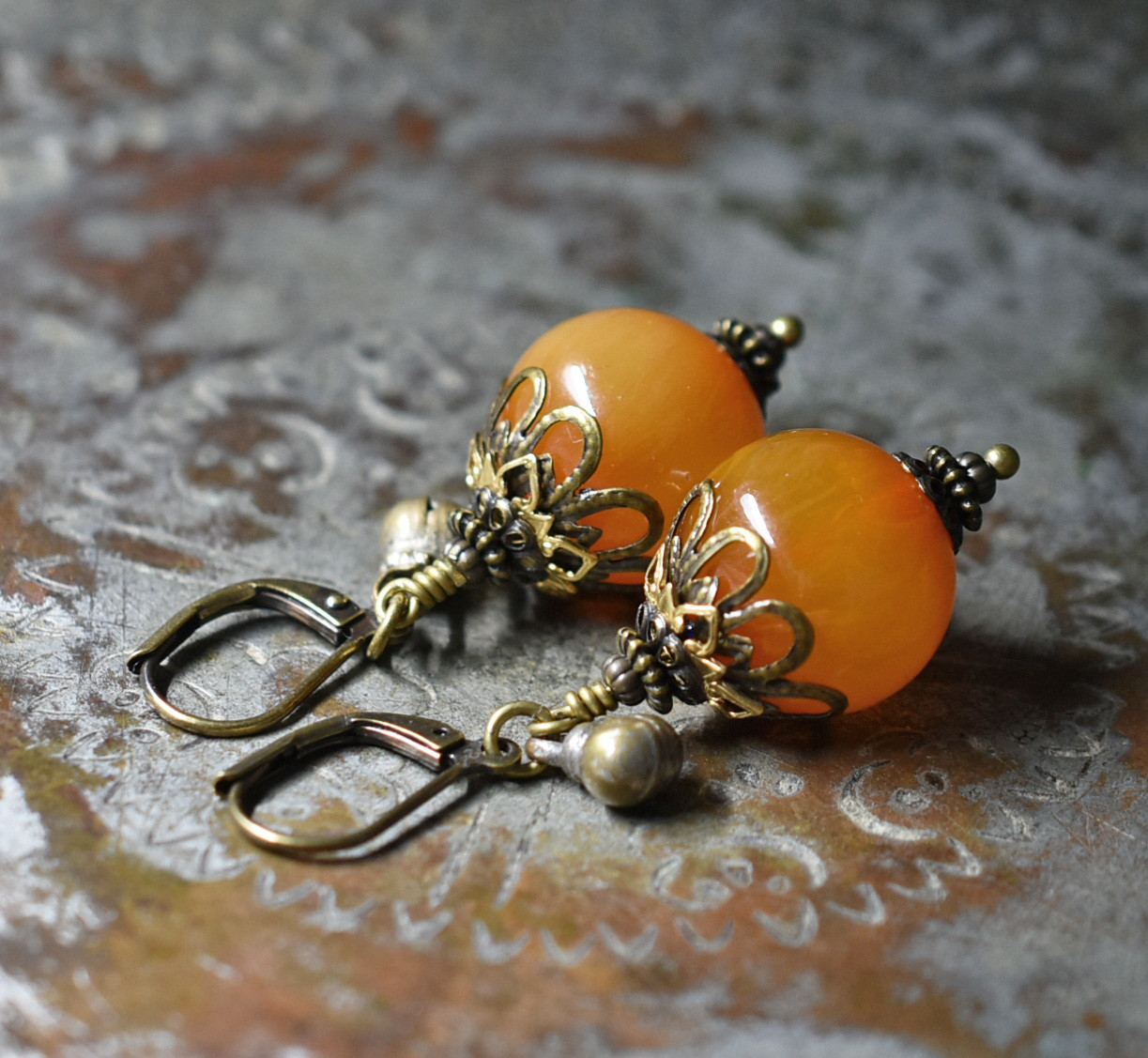 まん丸艶やかなアフリカンアンバーと民族鈴のピアス（淡）