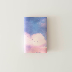 平裝書大小的書，描繪了粉紅色的雲朵和湖泊 第1張的照片