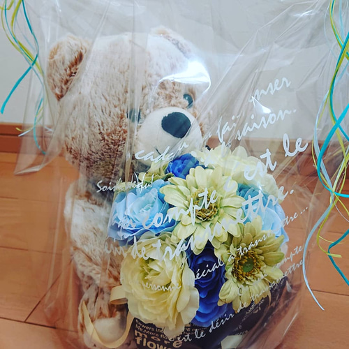 青い合成花で作られたクマ型のぬいぐるみと白い花束のセット,