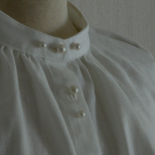 リネン100％ スタンドカラーの白ブラウス クリームパールボタン