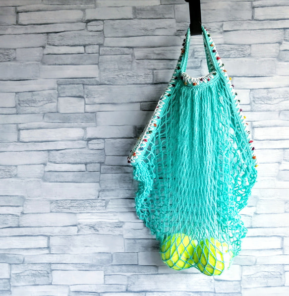 手編みのポンポン毛糸で飾ったネットバッグ　ターコイズブルー　メッシュバッグ　マルシェバッグ　エコバッグ　コンパクト 3枚目の画像