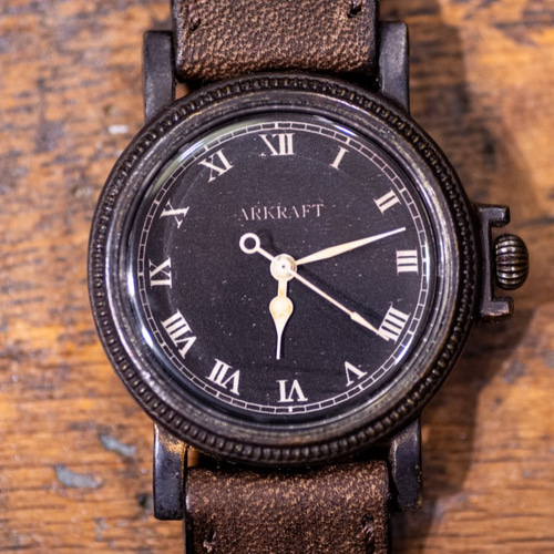 ヴィンテージ感のあるコインエッジケースの黒い文字盤の腕時計