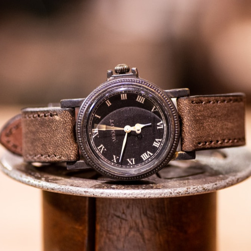 ヴィンテージ感のあるコインエッジケースの黒い文字盤の腕時計(Nes