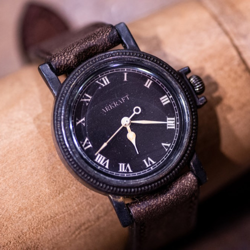 ヴィンテージ感のあるコインエッジケースの黒い文字盤の腕時計